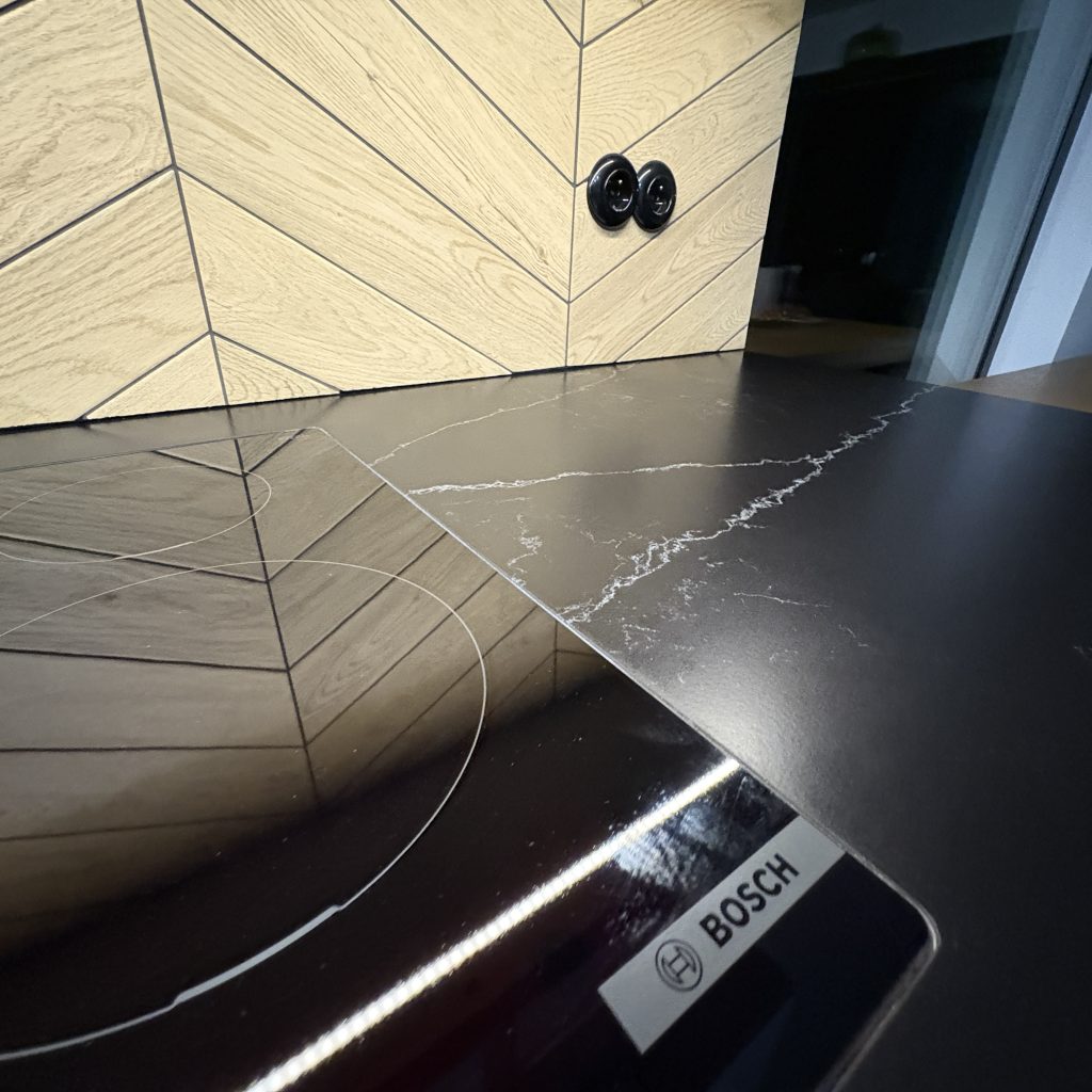 blaty kuchenne z konglomeratu nero venato w satynie - widok na płytę indukcyjną licowaną z blatem